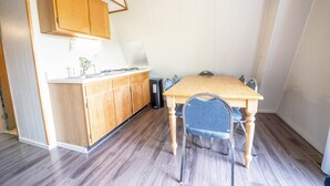 A compact kitchen with wooden cabinets, a dining table with chairs, and a trash bin. - A-Frame Cabin on Table Rock Lake, by SDC! (Branson)