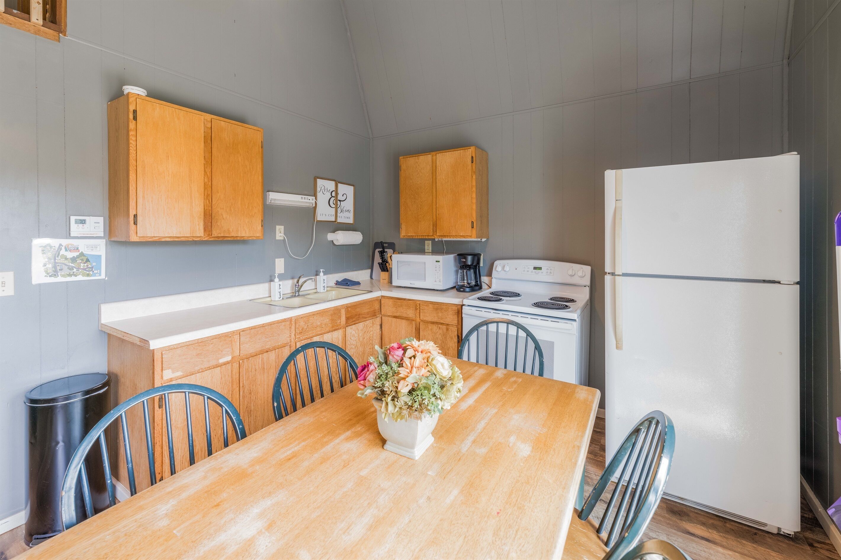 A kitchen with wooden cabinets, a white refrigerator, a stove, and a dining table with chairs.
