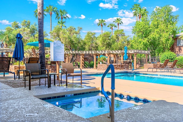 Un espace piscine comprenant des chaises longues, un jacuzzi et une pergola.