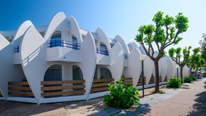 Un edificio moderno con architettura dalle linee curve originali, un vialetto lastricato e alberi lungo il lato.