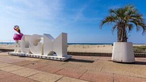 Un grande cartello bianco con la scritta "LAGU" e una scultura di fenicottero rosa.