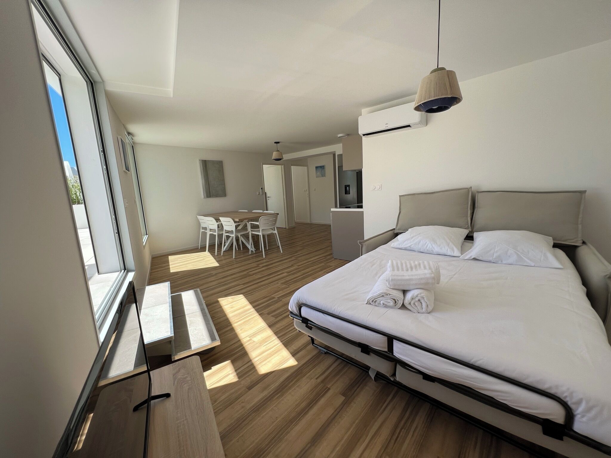 A modern hotel room with a large bed, a desk, a chair, and a dining table.