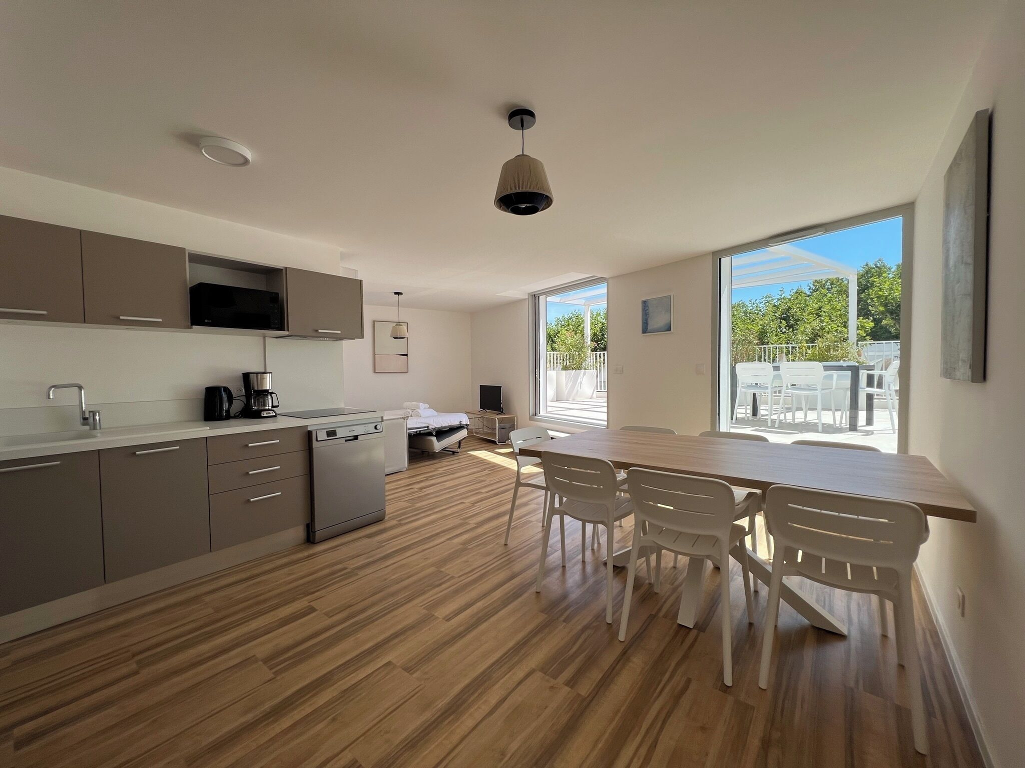 A modern kitchen with a dining area, large windows, and a view of the outdoors.