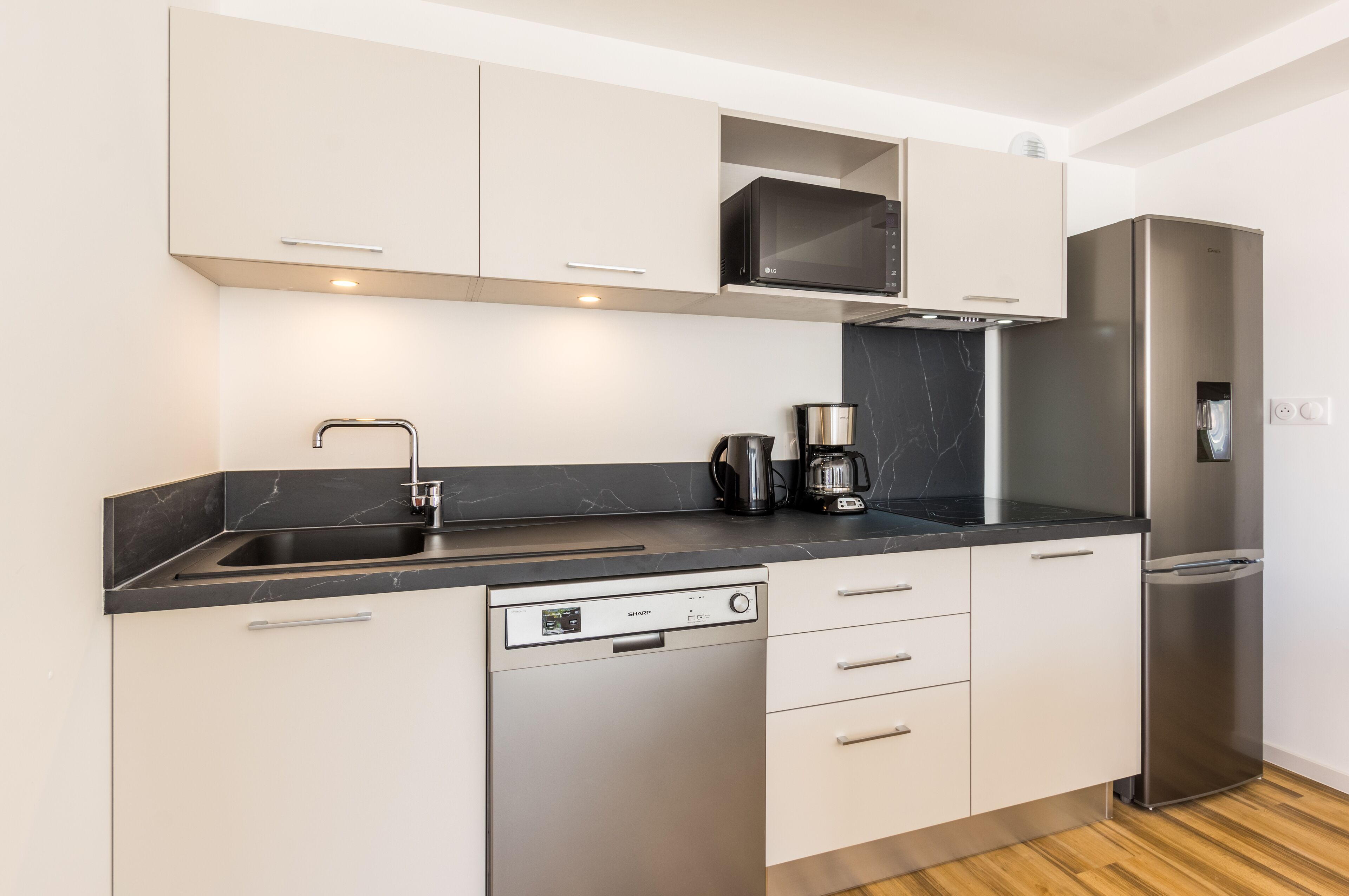 Eine moderne Küche mit Geschirrspüler, Mikrowelle, Kaffeemaschine und Kühlschrank.