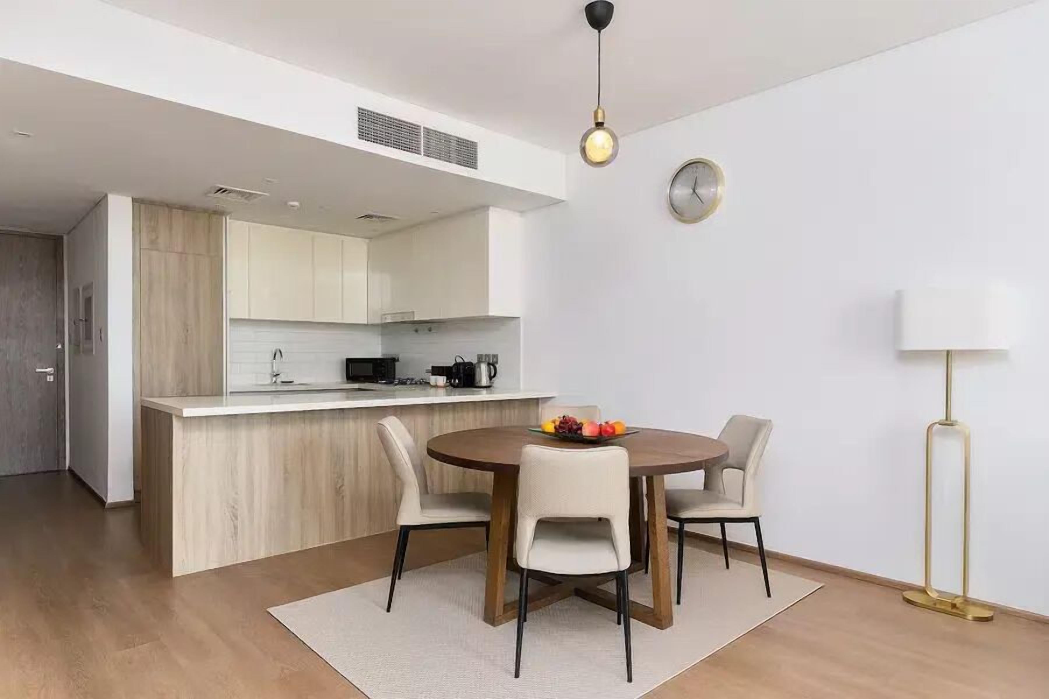 A modern kitchen with a central island, a dining area with a round table and four chairs, and a floor lamp.