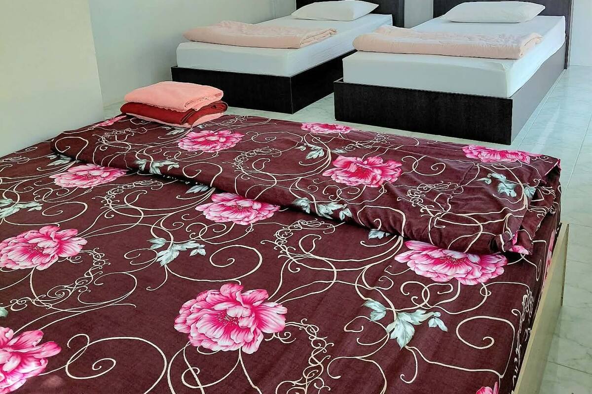 A hotel room with two beds, a TV, and a window with curtains.