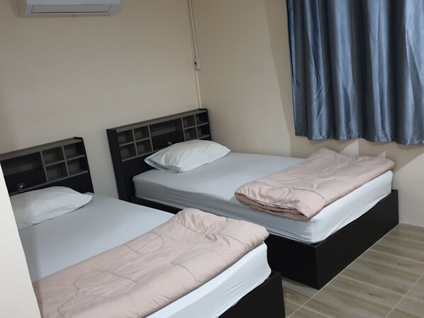 Two single beds with headboards, a wall-mounted air conditioner, and a window with blue curtains. - Ozone at farm (Chom Bueng)