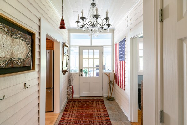 Classic hallway with a traditional design, featuring a patterned rug, chandelier, and glass door.