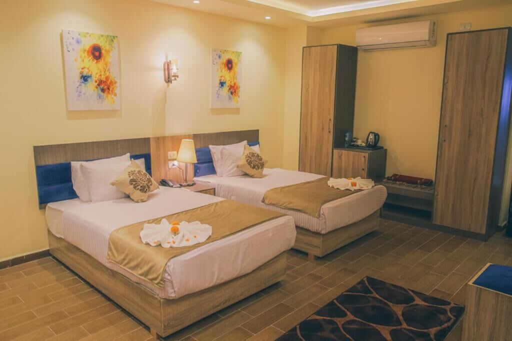 Habitación de hotel con dos camas, un escritorio y un armario.