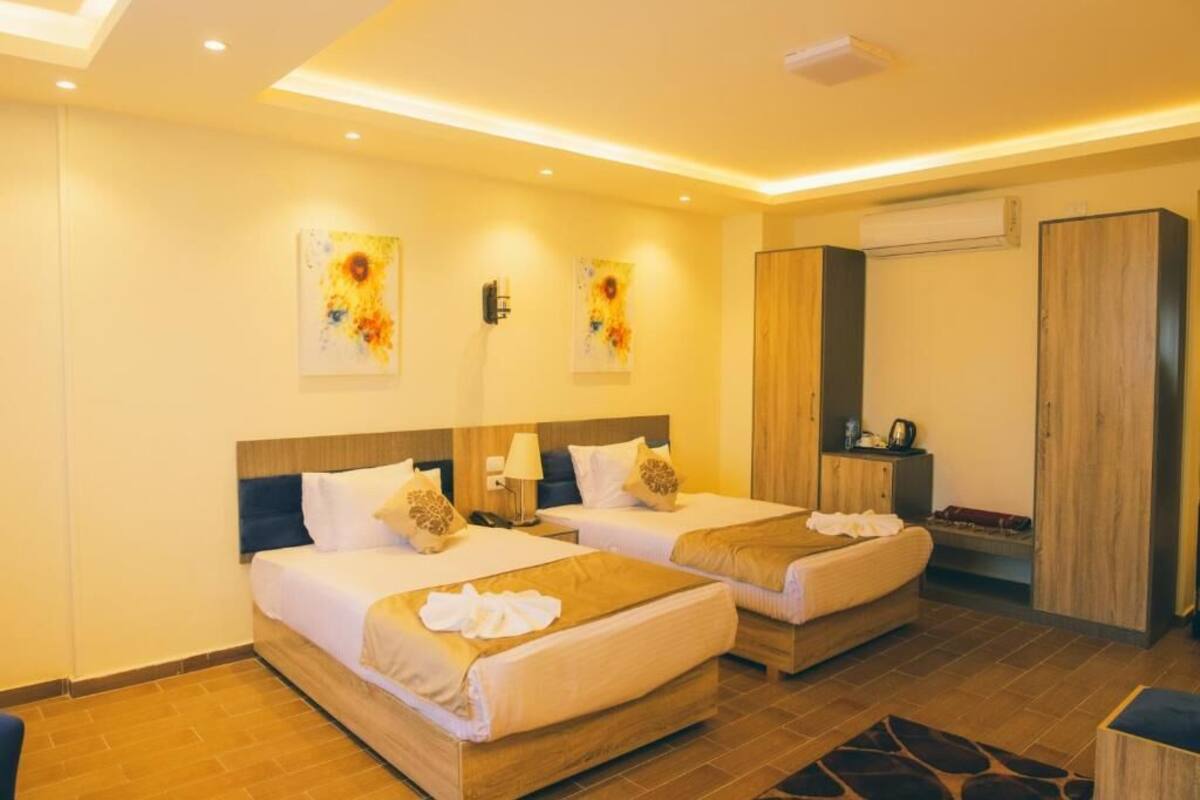 A hotel room with two beds, a desk, and a wardrobe.