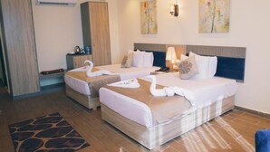 Una camera d'albergo con due letti, un armadio, una scrivania e opere d'arte alle pareti.