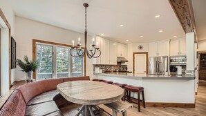 A modern kitchen with a large island, wooden flooring, and a built-in bench seating area. - 1890 Lions Ridge Loop, #9-West Vail Remodeled Home, Hot Tub, On Bus Route, Close to Vail! (Vail)