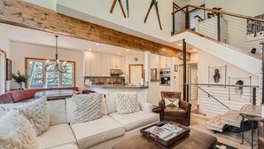 A spacious living room with a white sofa, a coffee table, and a staircase leading to an upper level. - 1890 Lions Ridge Loop, #9-West Vail Remodeled Home, Hot Tub, On Bus Route, Close to Vail! (Vail)