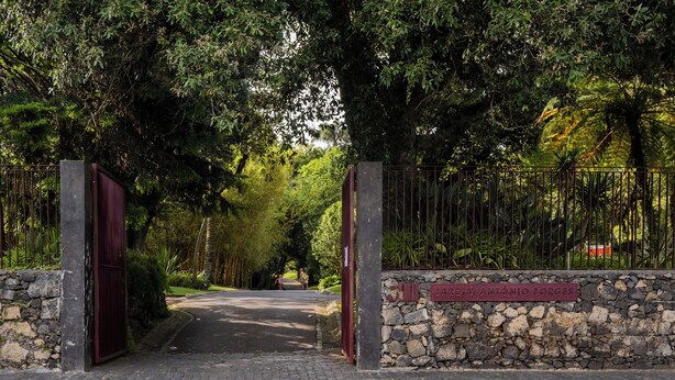 A paved pathway leading to a gated entrance with a stone wall and a sign reading "JARDIM ANTONIO BORGES". - Botanic Garden Duplex (Ponta Delgada)