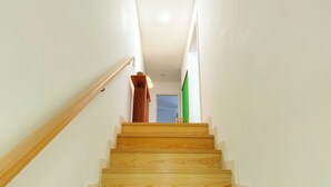 A wooden staircase with a handrail leading to a landing. - Botanic Garden Duplex (Ponta Delgada)