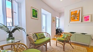 A room with wicker chairs, a small table with a plant, and a cabinet. - Botanic Garden Duplex (Ponta Delgada)