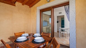 A wooden dining table with plates and glasses, a wooden ceiling, and a doorway leading to another room.