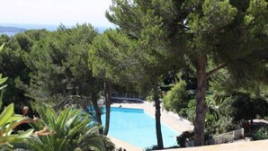 A pool surrounded by trees, with a view of the sea in the background. - Les Pieds Dans L'eau, la Tête Dans les Étoiles (HYERES)