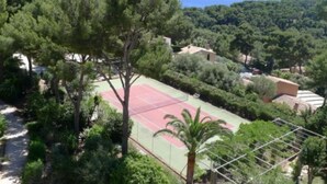 A tennis court surrounded by dense greenery and a view of the sea. - Les Pieds Dans L'eau, la Tête Dans les Étoiles (HYERES)