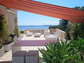 En terrasse med udendørs møbler, havudsigt og et pergola-tag.