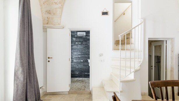 A staircase leading to a second floor, a door with a stone facade, and a chair in the foreground. - Casa Carducci by Wonderful Italy (Ostuni)