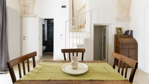 A dining area with a table set for two, a pitcher on the table, and a staircase leading to an upper level. - Casa Carducci by Wonderful Italy (Ostuni)