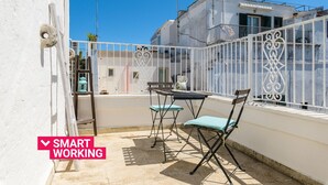 An outdoor balcony with a table and chairs, a white railing, and a clear blue sky. - Casa Carducci by Wonderful Italy (Ostuni)