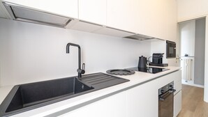 Una cucina moderna con lavello nero, macchina per caffè e forno a microonde.