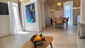 A spacious living area with a wooden coffee table, a dining table, and a kitchen in the background.