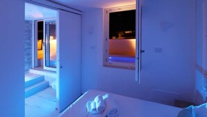 A bedroom with a bed, a window, and a door leading to a balcony.