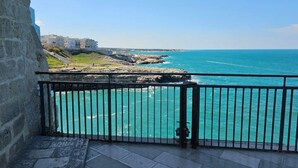 A balcony with a view of the sea and buildings in the background.