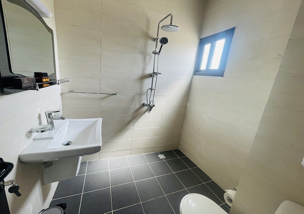 A small bathroom with a white sink, a shower, and a toilet.