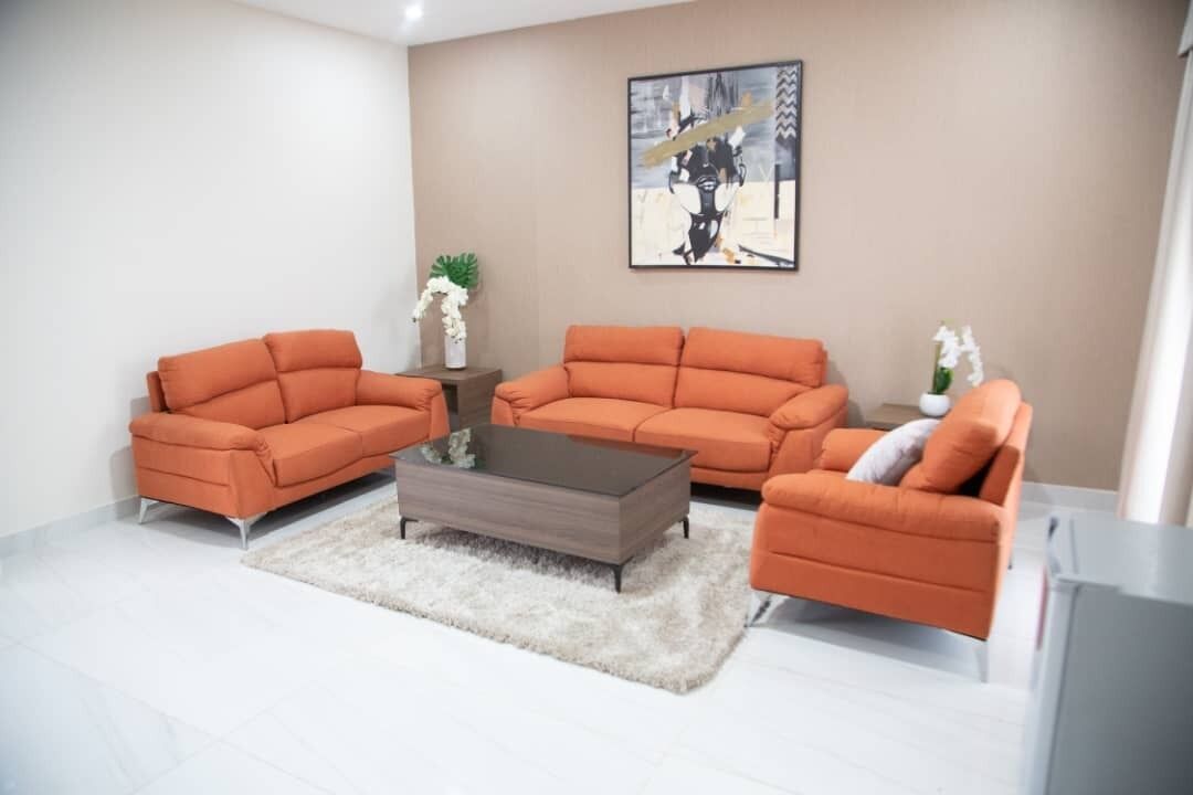 A living room with two orange sofas, a coffee table, and a painting on the wall.
