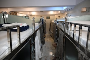 A narrow corridor with bunk beds, each with a metal railing and a white mattress. - Sagar Dormitory Andheri - Nearest to Andheri Railway Station West (Mumbai)