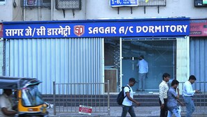 A dormitory building with a signboard in a local language, a metal gate, and a few pedestrians. - Sagar Dormitory Andheri - Nearest to Andheri Railway Station West (Mumbai)