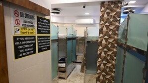 A hotel bathroom with glass partitions, a no smoking and alcohol sign, and a CCTV warning. - Sagar Dormitory Andheri - Nearest to Andheri Railway Station West (Mumbai)