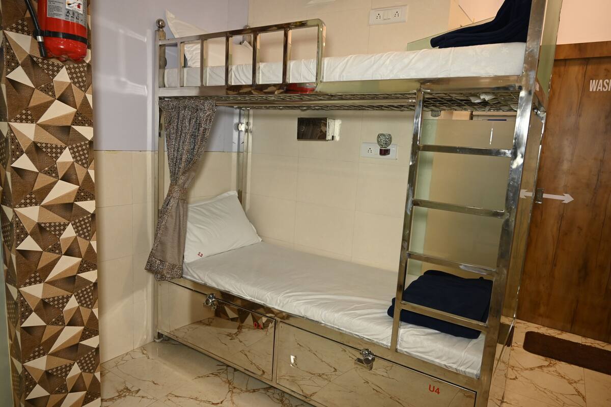 A bunk bed with a storage drawer, a fire extinguisher, and a patterned wall.