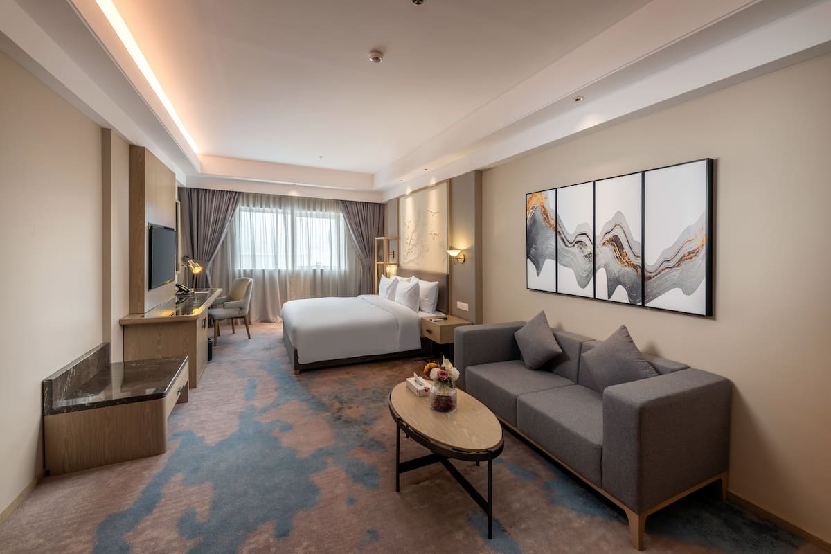 Ein modernes Hotelzimmer mit Bett, Sofa, Schreibtisch und Kunstwerken an der Wand.