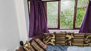 Une pièce chaleureuse avec une grande fenêtre, un canapé agrémenté de coussins à motifs et un tapis bleu à poils longs.