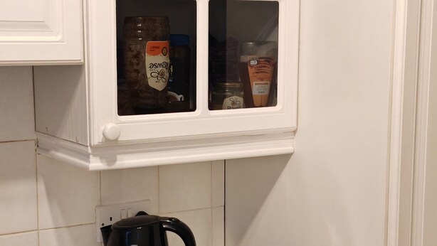 Une cuisine équipée d’une cuisinière, d’une bouilloire et de trois récipients étiquetés pour le thé, le sucre et le café.