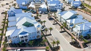 Un quartier résidentiel composé de nombreuses maisons à deux étages, caractérisées par des toits bleus et des murs blancs, disposées selon un plan en forme de grille autour d’une rue centrale.