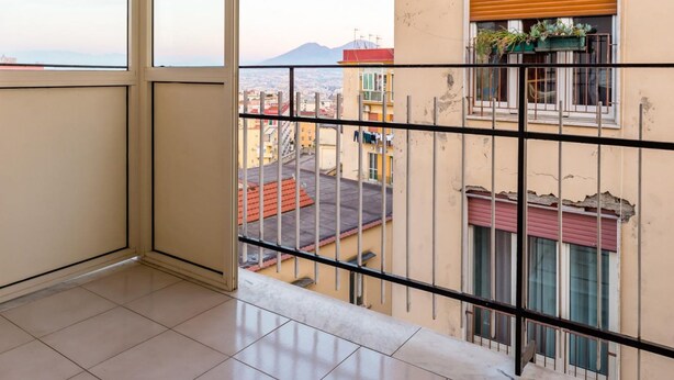 A balcony with a metal railing, a view of the cityscape, and a building with a red roof. - Appartamento all Arenella by Wonderful Italy (Naples)