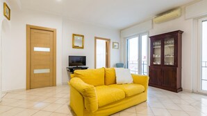 A living room with a yellow sofa, a television, a cabinet, and a door. - Appartamento all Arenella by Wonderful Italy (Naples)