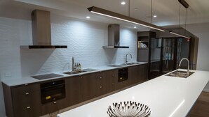 A modern kitchen with a large island, built-in oven, and stainless steel appliances. - Mackay Adventure Lodge (Andergrove)