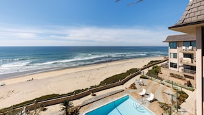 Ein Strandhotel mit Schwimmbad, Meerblick und einem Balkon mit Sitzgelegenheit.