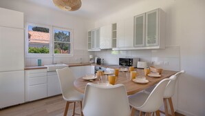 Une cuisine moderne avec des meubles blancs, une table à manger en bois et des chaises blanches.
