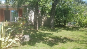 Una casa pequeña con un patio, rodeada de árboles y un jardín.