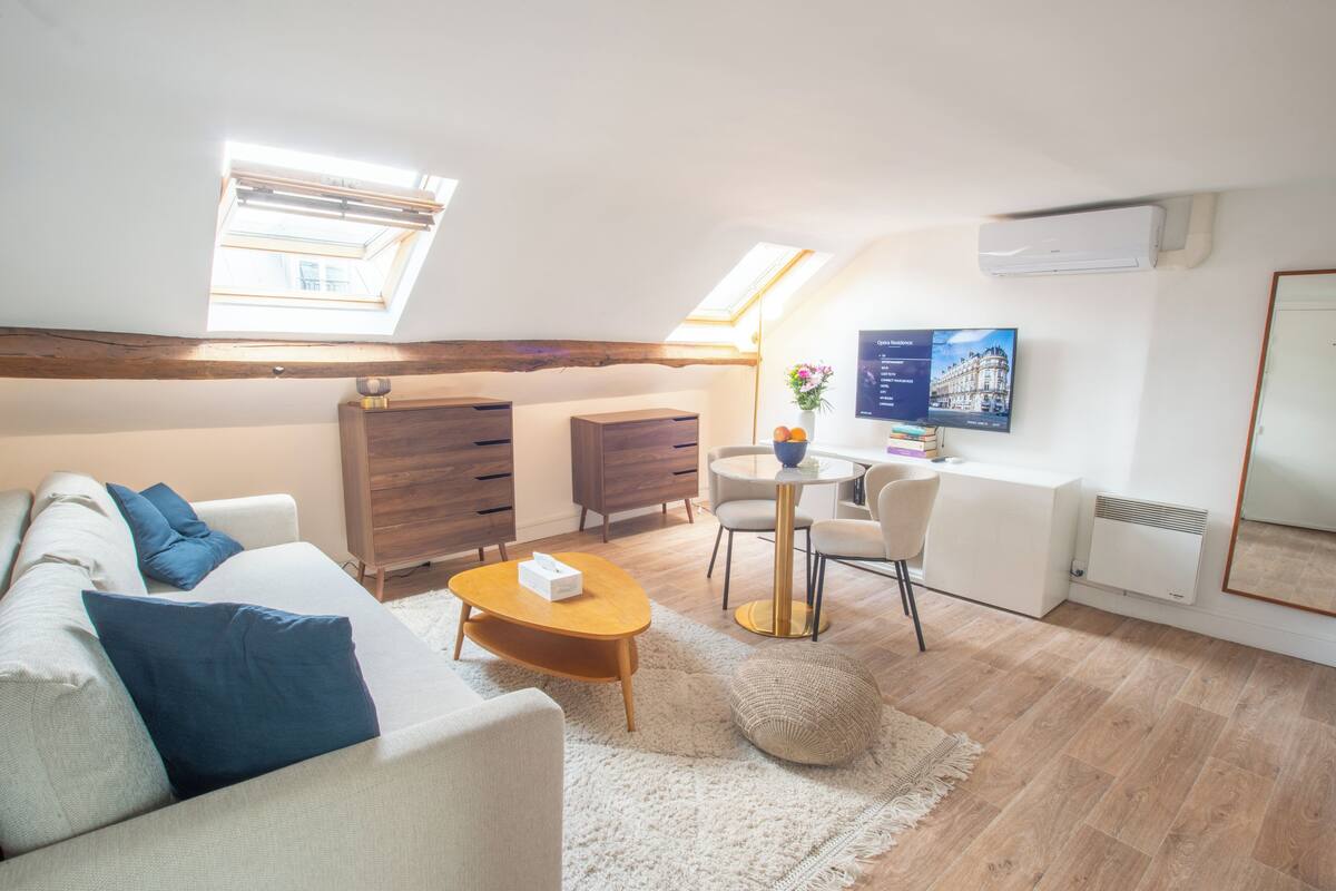 A modern living room with a sofa, coffee table, and a dining area with chairs and a small table.