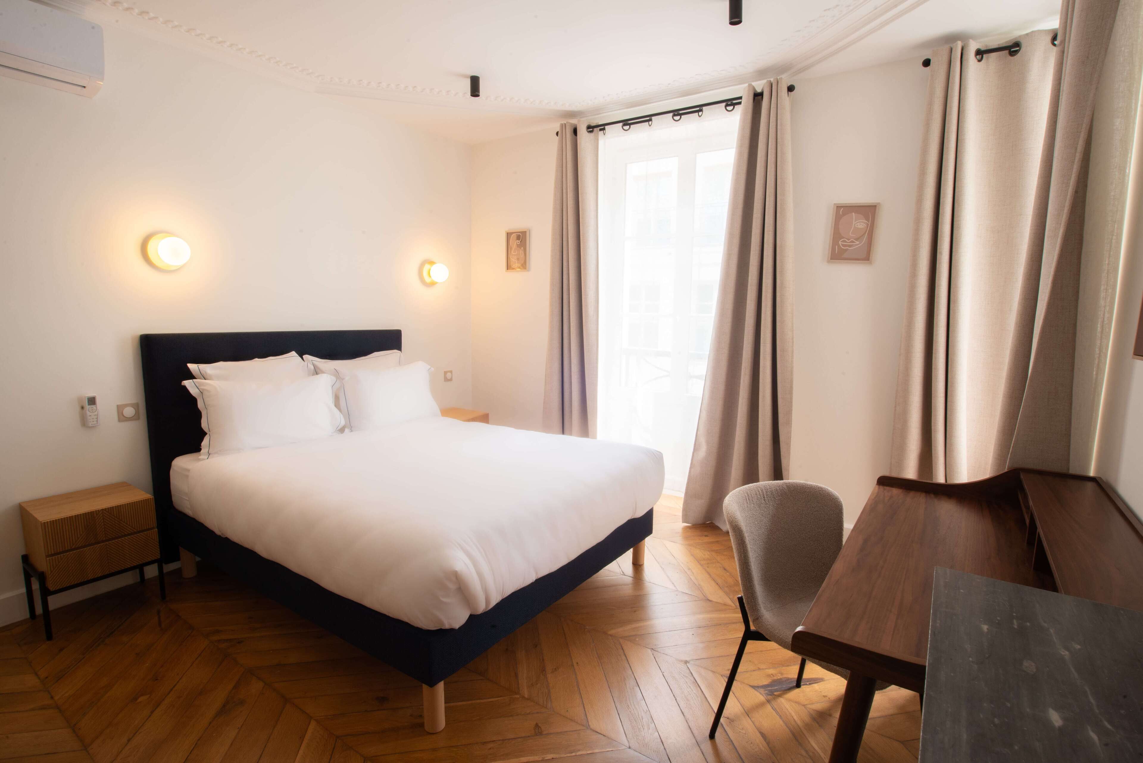 A bedroom with a bed, bedside tables, a chair, and a desk.