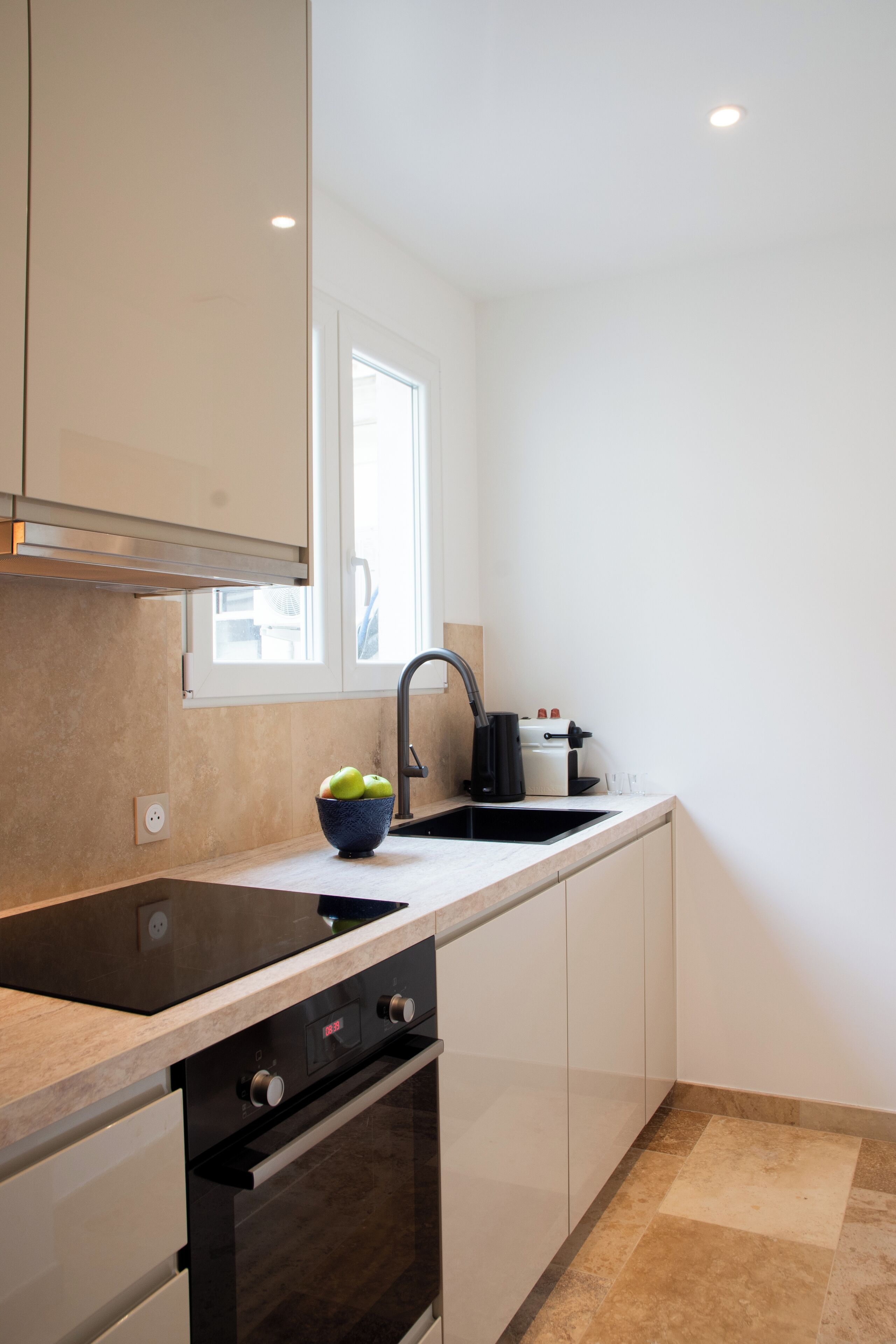 Een moderne keuken met een zwart fornuis, een spoelbak en een raam boven de aanrecht.